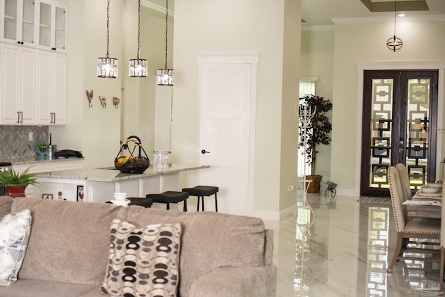 kitchen featuring a breakfast bar area, hanging light fixtures, ornamental molding, decorative backsplash, and white cabinets