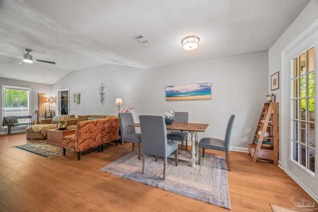 dining space featuring a textured ceiling, light wood finished floors, ceiling fan, and vaulted ceiling