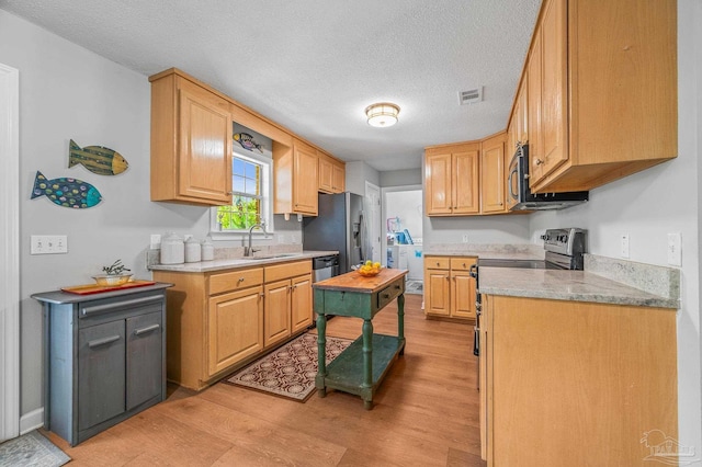 kitchen featuring light wood-style flooring, visible vents, a sink, light countertops, and stainless steel appliances