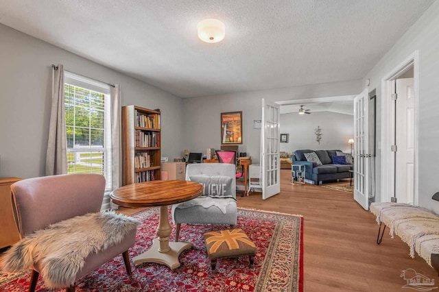 living area with a textured ceiling, french doors, and wood finished floors