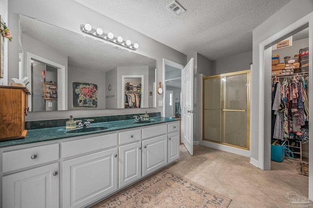 full bathroom with a shower stall, double vanity, visible vents, and a sink