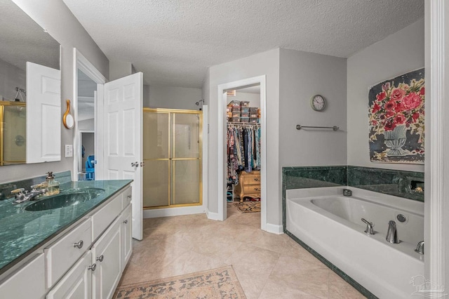 full bathroom with a shower stall, a bath, a textured ceiling, vanity, and a walk in closet