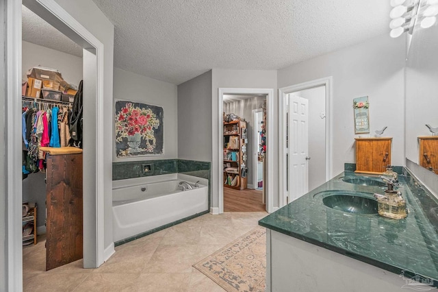 bathroom with a bath, tile patterned flooring, a sink, a walk in closet, and double vanity