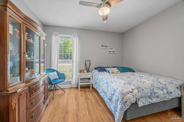 bedroom featuring light wood finished floors, a textured ceiling, and ceiling fan