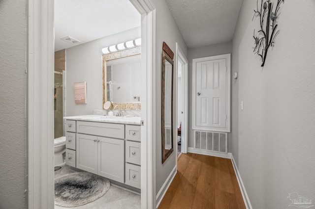 bathroom with visible vents, baseboards, vanity, and wood finished floors