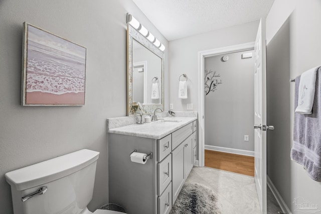 bathroom featuring toilet, vanity, and a textured ceiling