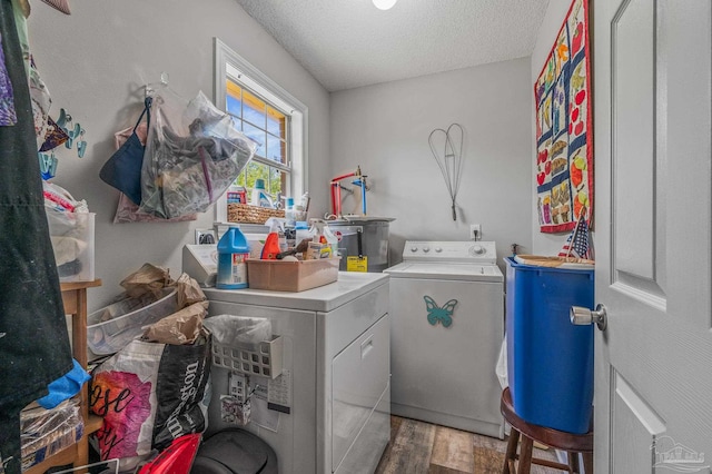 clothes washing area with laundry area, a textured ceiling, wood finished floors, water heater, and washer and clothes dryer