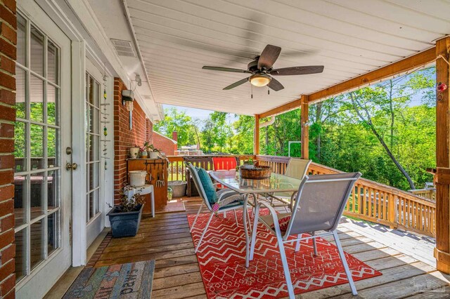 wooden terrace with outdoor dining space, french doors, and ceiling fan