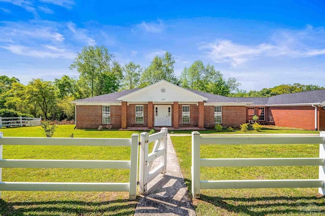 ranch-style house featuring brick siding, a front lawn, and a fenced front yard