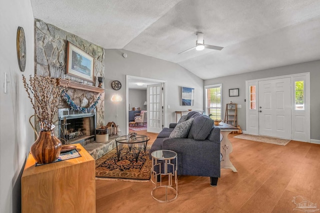 living room featuring a healthy amount of sunlight, a textured ceiling, wood finished floors, and lofted ceiling