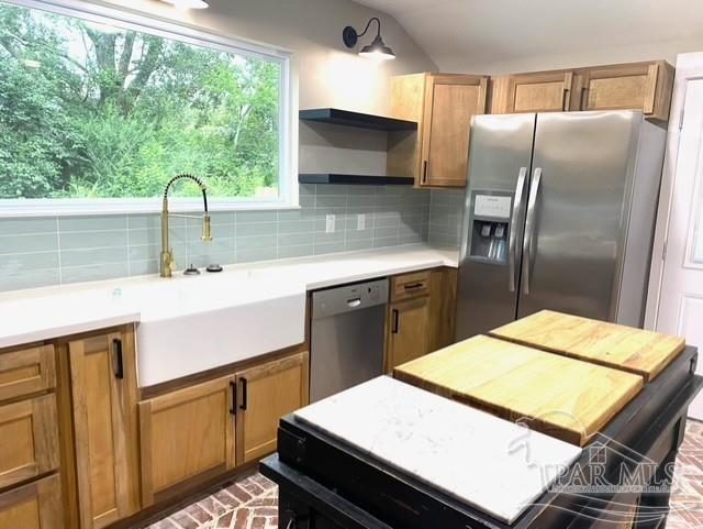 kitchen with stainless steel appliances, a sink, decorative backsplash, open shelves, and brown cabinetry