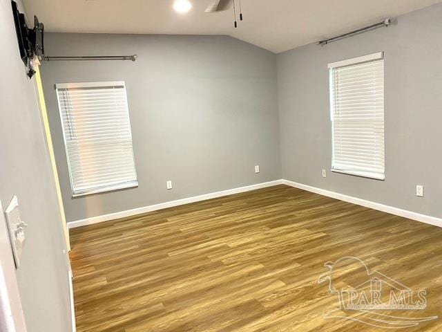 spare room with vaulted ceiling, wood finished floors, a ceiling fan, and baseboards