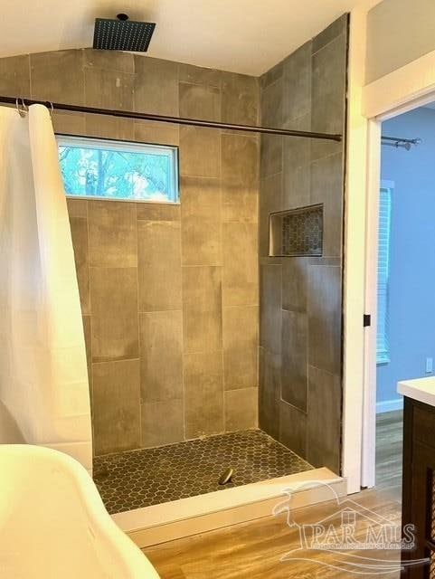 bathroom with tiled shower and vanity