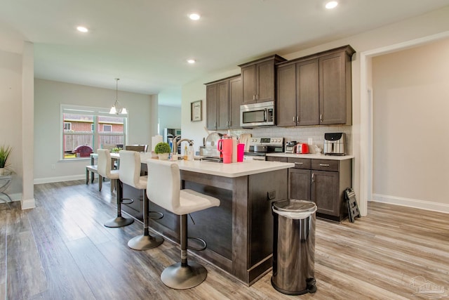 431 Broadleaf Cir, Cantonment, FL 32533 - kitchen with stainless steel appliances, a center island with sink, light wood-style floors, baseboards, and tasteful backsplash