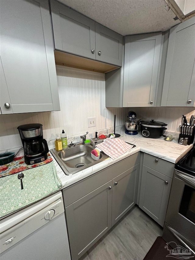 kitchen with range with electric cooktop, sink, white dishwasher, light hardwood / wood-style floors, and gray cabinets