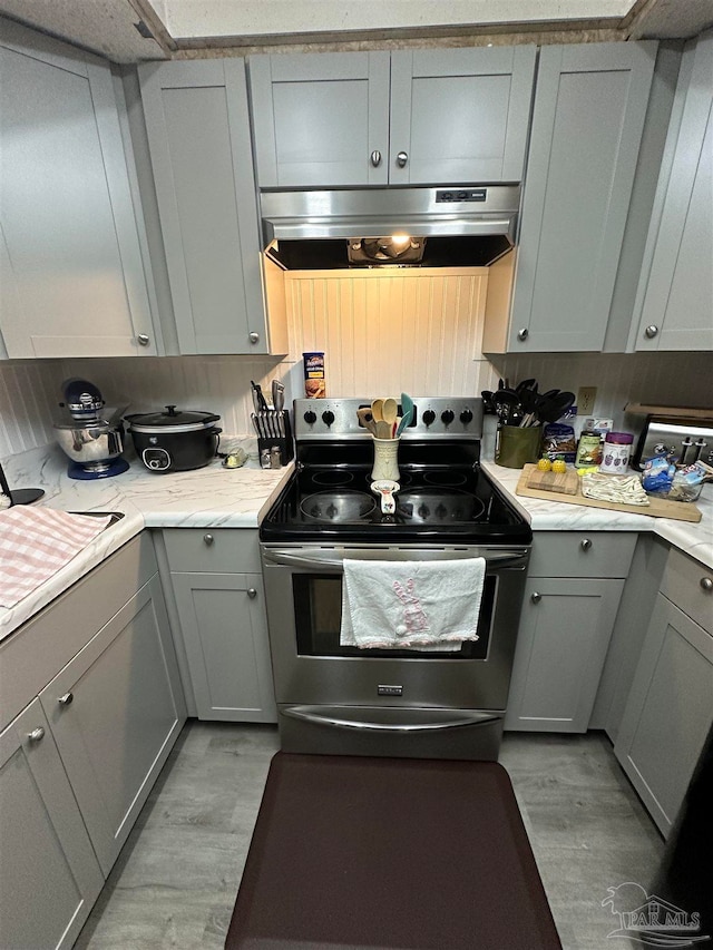 kitchen featuring light hardwood / wood-style floors, stainless steel electric stove, gray cabinetry, and range hood