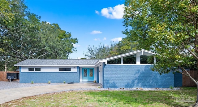 ranch-style home featuring french doors and a front lawn