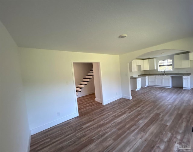 unfurnished living room featuring sink and dark hardwood / wood-style floors