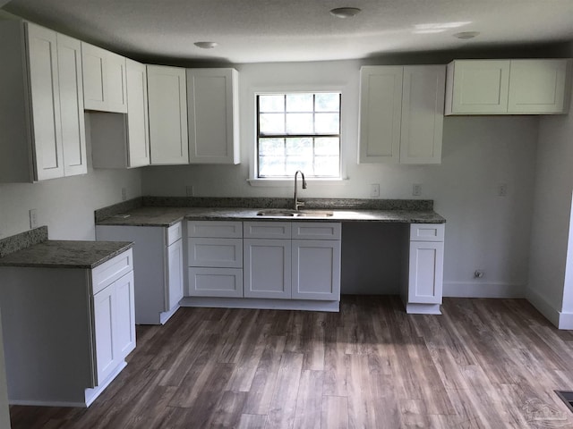 kitchen featuring white cabinetry, sink, dark stone counters, and dark hardwood / wood-style flooring