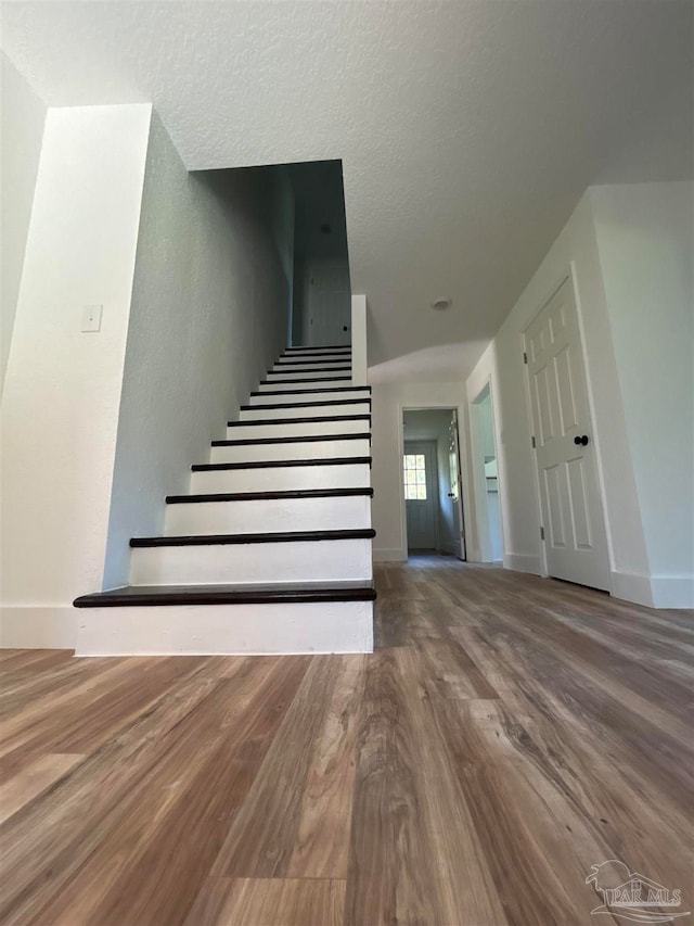 stairs featuring hardwood / wood-style flooring and a textured ceiling