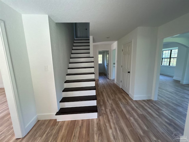 staircase with wood-type flooring and a textured ceiling