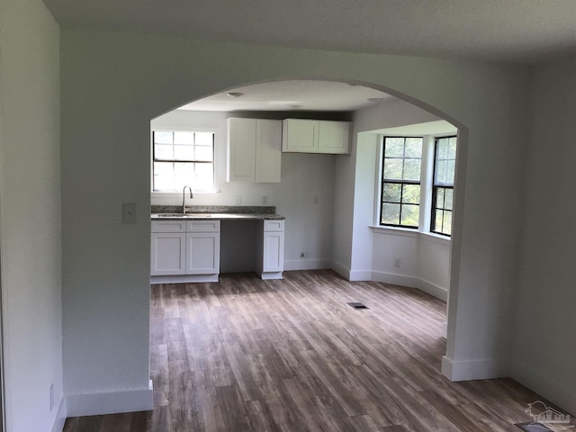 kitchen with white cabinetry, hardwood / wood-style flooring, sink, and a textured ceiling