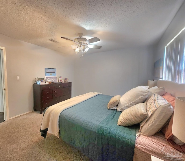bedroom featuring a textured ceiling, carpet flooring, a ceiling fan, and visible vents