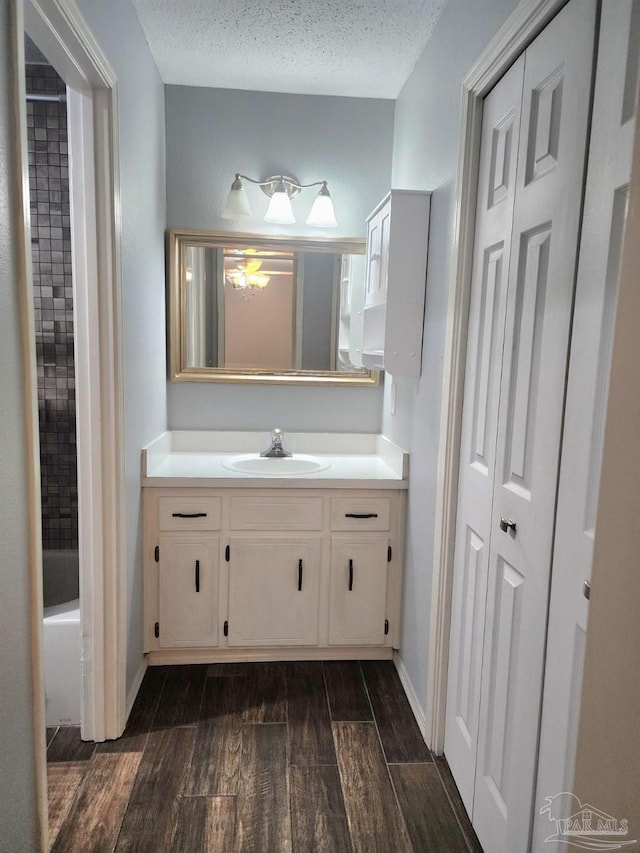 bathroom with wood finished floors, vanity, baseboards, and tub / shower combination