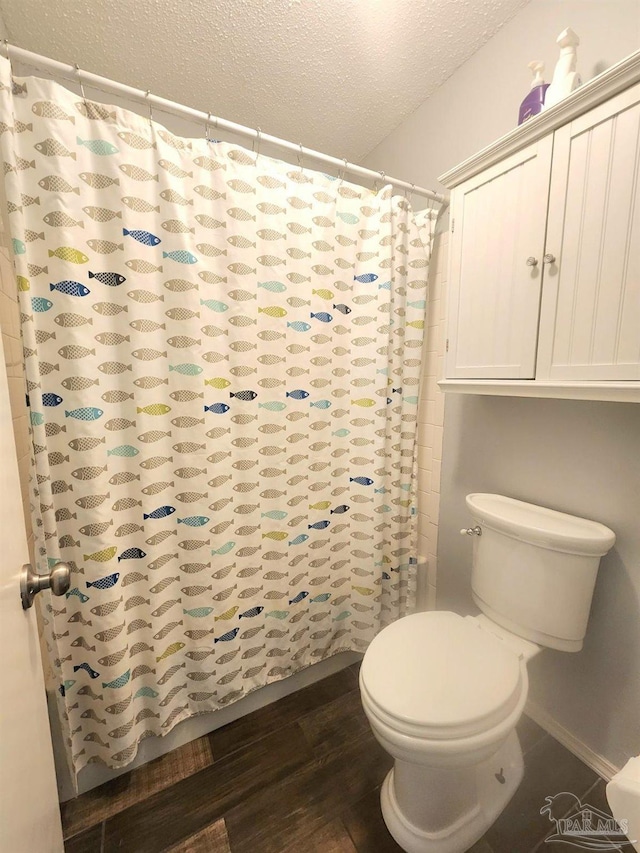 full bathroom with a shower with shower curtain, baseboards, a textured ceiling, toilet, and wood finished floors