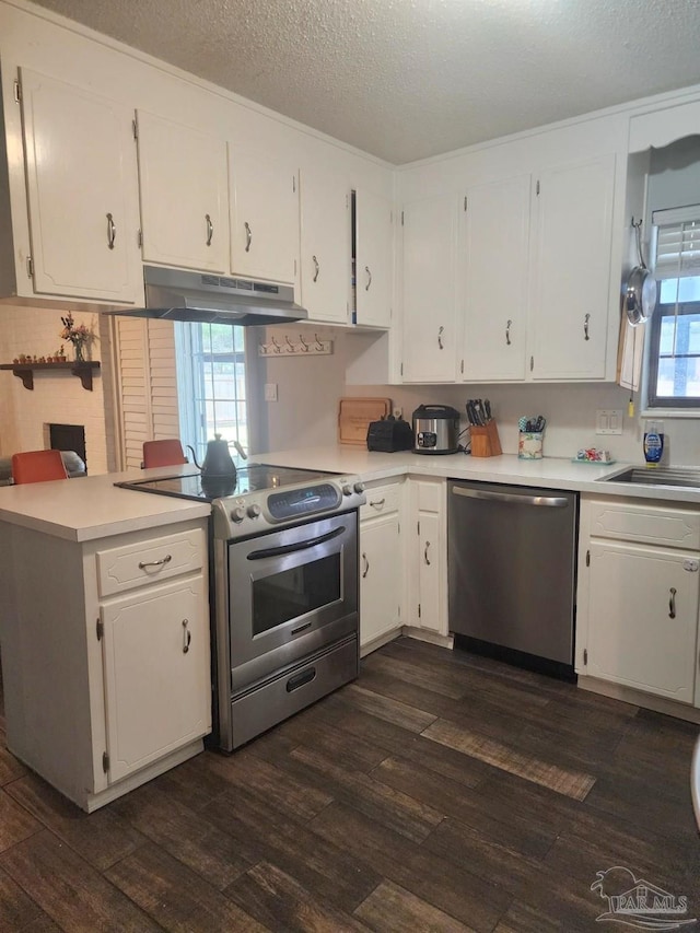 kitchen with stainless steel appliances, under cabinet range hood, dark wood-style flooring, and white cabinetry