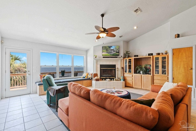 living room with a tile fireplace, high vaulted ceiling, ceiling fan, and light tile patterned floors