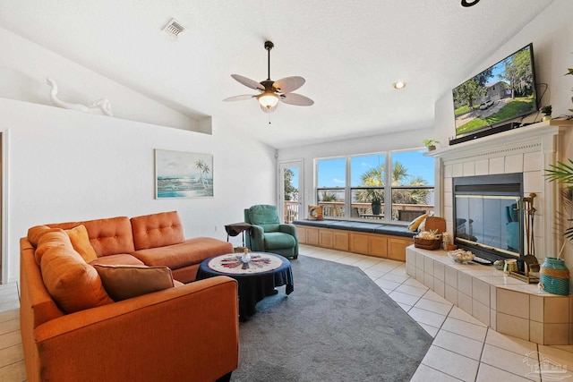 tiled living room with a tiled fireplace, a textured ceiling, ceiling fan, and lofted ceiling