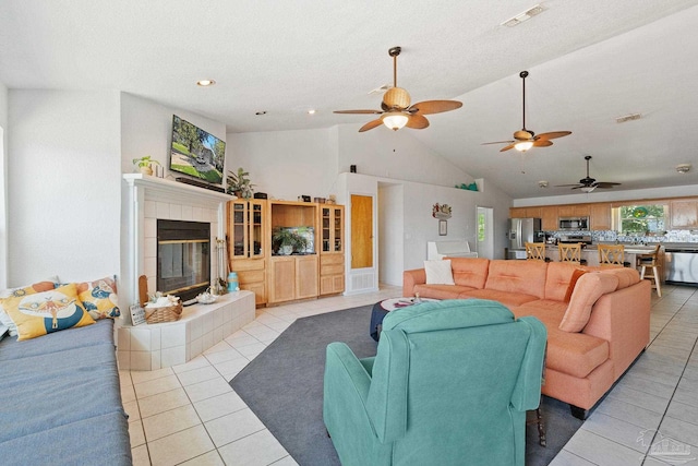 tiled living room featuring a tile fireplace, ceiling fan, and high vaulted ceiling