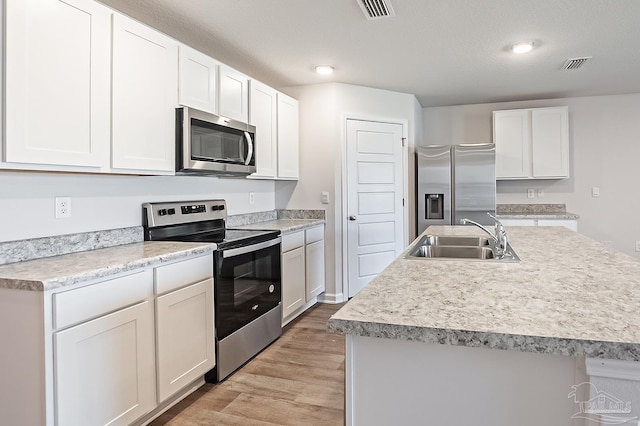 7581 Steeplechase Blvd, Pensacola, FL 32526 - kitchen featuring stainless steel appliances, light wood-style floors, white cabinetry, an island with sink, and light countertops