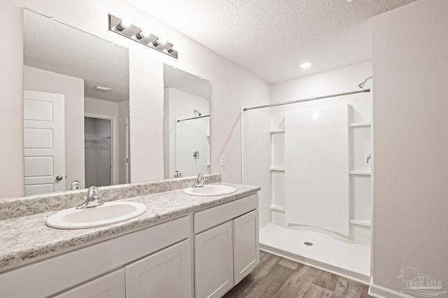 7581 Steeplechase Blvd, Pensacola, FL 32526 - full bathroom featuring wood finished floors, double vanity, a shower stall, a textured ceiling, and a walk in closet