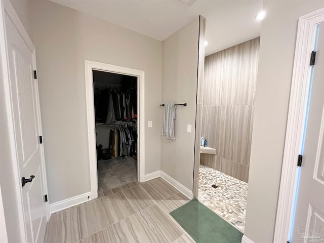 bathroom with recessed lighting, a spacious closet, baseboards, and a walk in shower