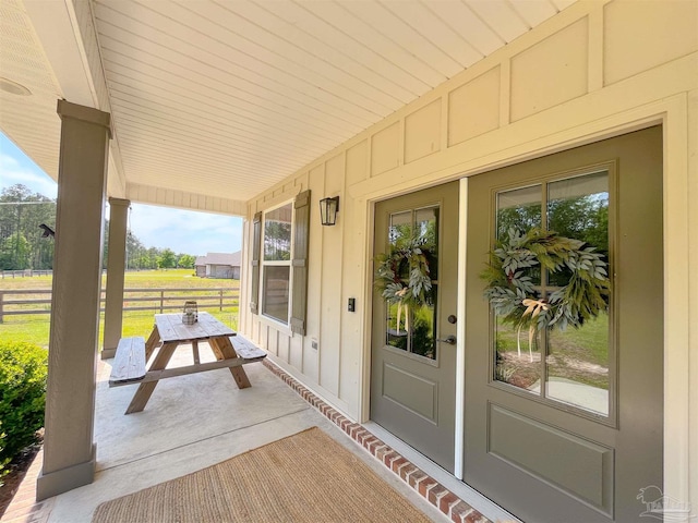 doorway to property with fence, a porch, and board and batten siding