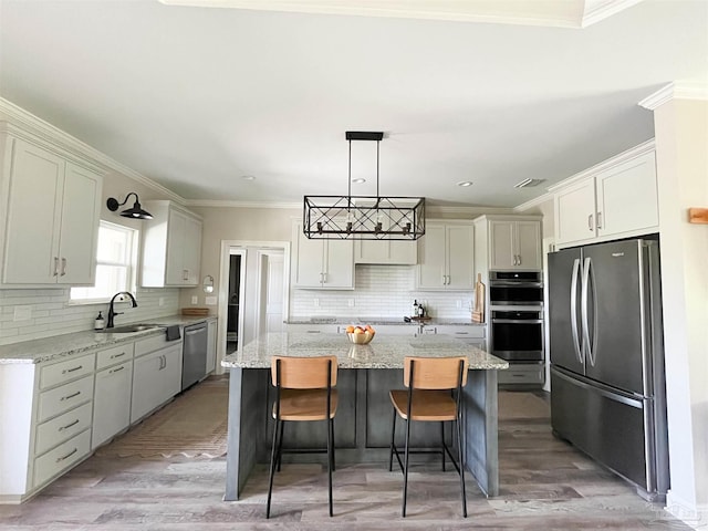 kitchen featuring tasteful backsplash, a kitchen island, appliances with stainless steel finishes, and a sink
