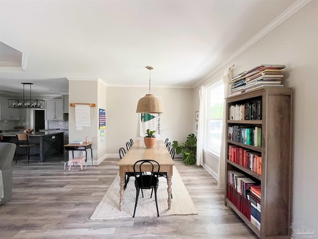 dining space featuring light wood-style floors, crown molding, and baseboards
