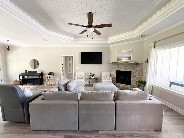 living area with a tray ceiling, ceiling fan, crown molding, wood ceiling, and a fireplace