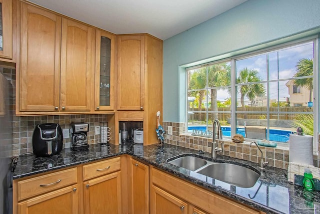 kitchen with dark stone countertops, sink, and tasteful backsplash