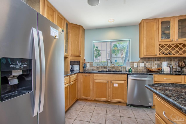 kitchen featuring dark stone counters, light tile patterned flooring, backsplash, stainless steel appliances, and sink