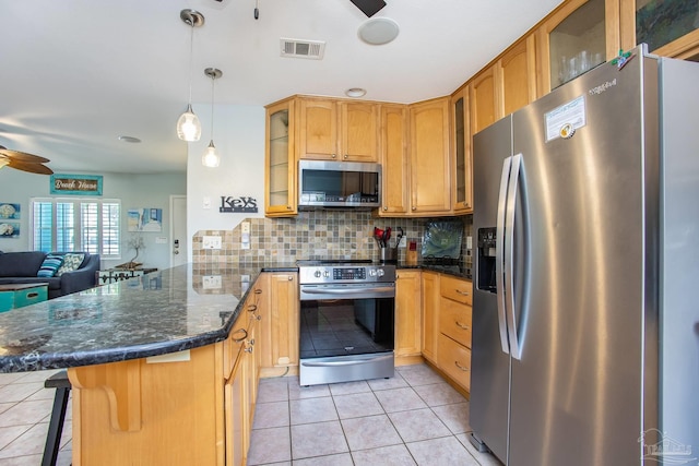 kitchen with light tile patterned flooring, stainless steel appliances, backsplash, ceiling fan, and a kitchen bar