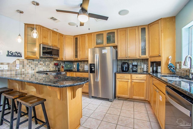 kitchen with appliances with stainless steel finishes, dark stone countertops, tasteful backsplash, and light tile patterned floors