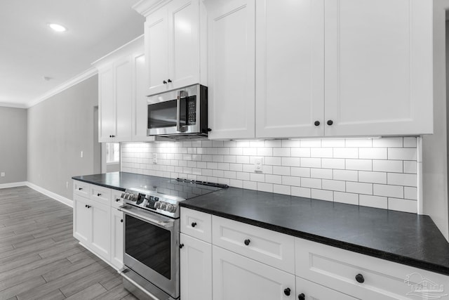 kitchen with stainless steel appliances, tasteful backsplash, light hardwood / wood-style floors, white cabinets, and ornamental molding