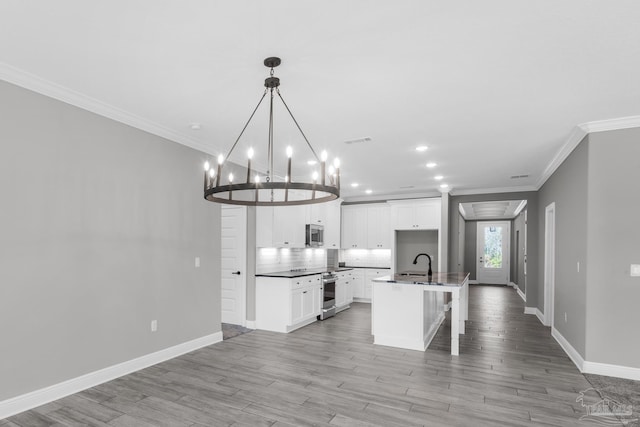 kitchen featuring pendant lighting, a center island with sink, white cabinets, light wood-type flooring, and stainless steel appliances