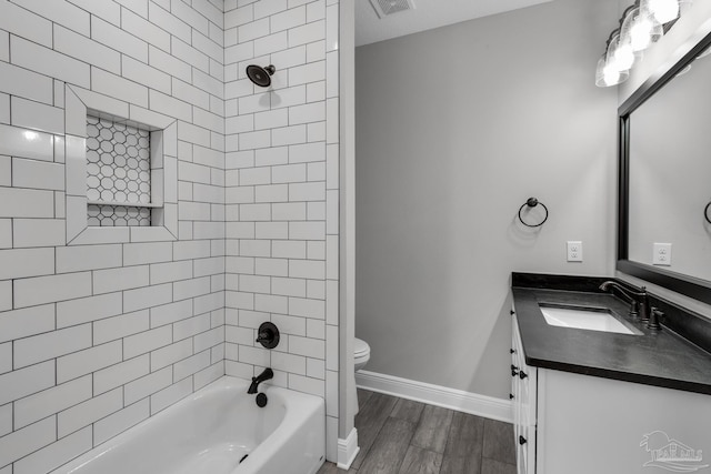 full bathroom featuring tiled shower / bath combo, toilet, wood-type flooring, and vanity