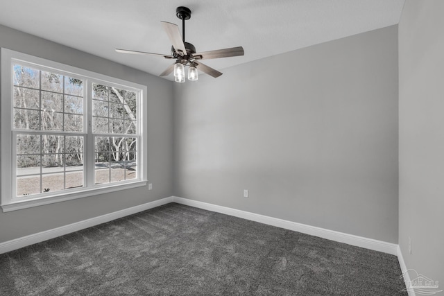 empty room with ceiling fan, dark carpet, and a wealth of natural light