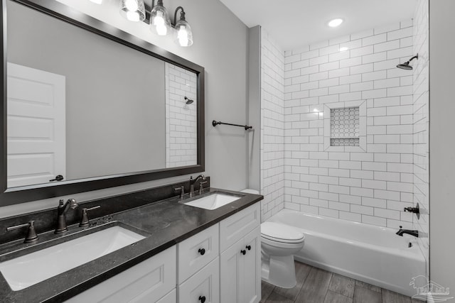 full bathroom featuring hardwood / wood-style floors, vanity, toilet, and tiled shower / bath