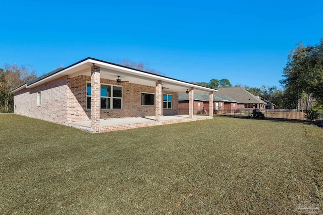 rear view of house featuring ceiling fan, a patio area, and a yard